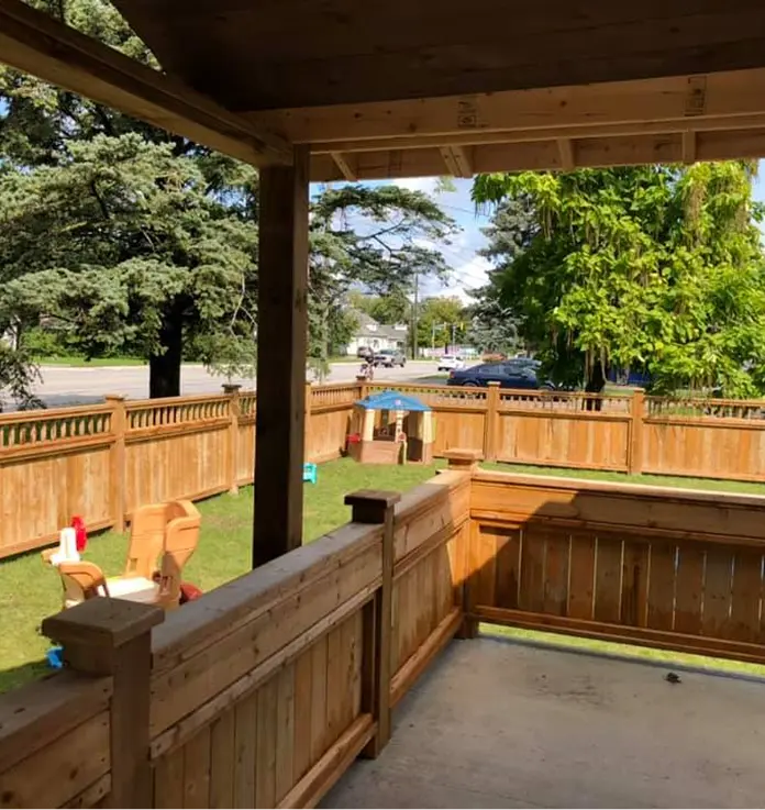 Covered outdoor play area overlooking the fenced daycare yard
