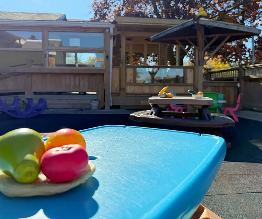 Learning Together Childcare outdoor play area with activity tables and a covered wooden structure