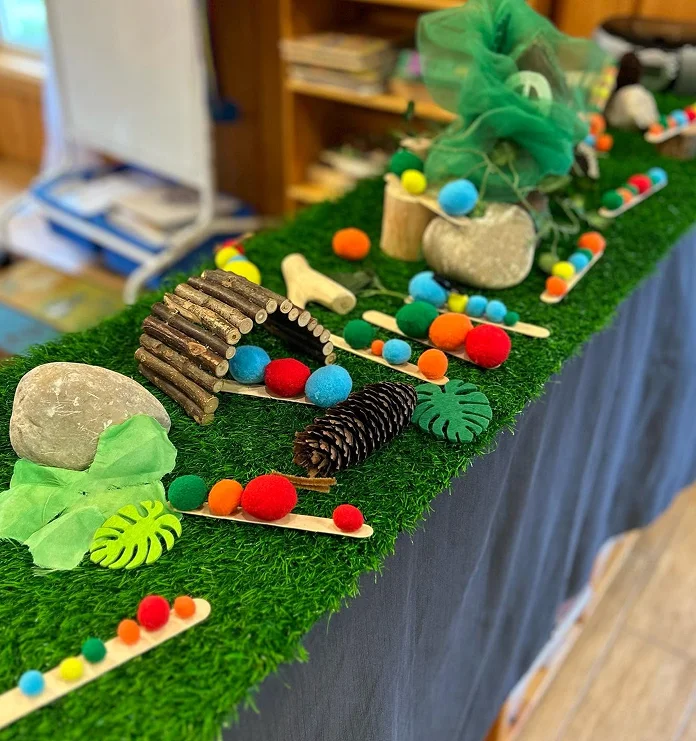 Nature-inspired sensory activity with colourful pom-poms, stones, sticks and pinecones at Learning Together Childcare